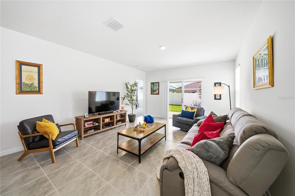 A kitchen with white cabinets, granite countertops, and an island opens to a dining area — 7104 CATTLE EGRET DRIVE, ST CLOUD, FL