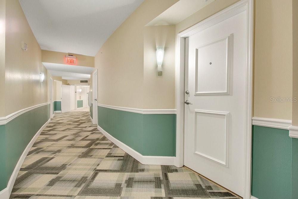A hallway with teal wainscoting, patterned carpet, and a white door on the right — 322 E CENTRAL BOULEVARD UNIT 1008, ORLANDO, FL