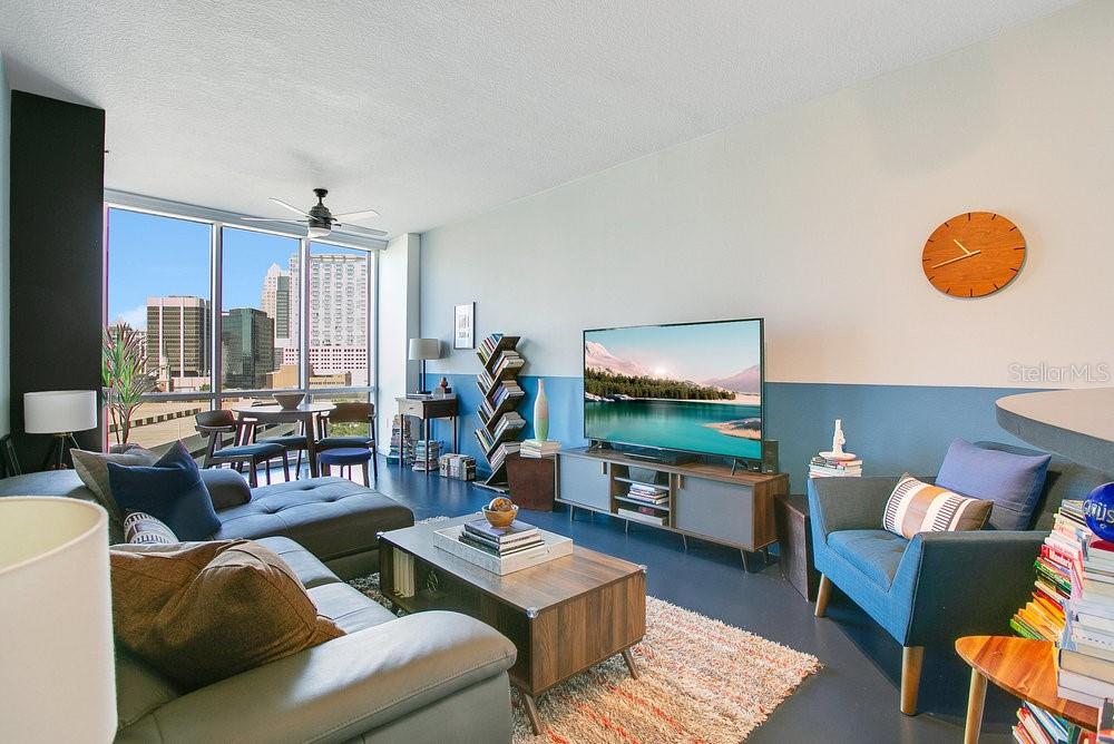 A modern living room features a large window with city views, a television, and furniture — 322 E CENTRAL BOULEVARD UNIT 1008, ORLANDO, FL