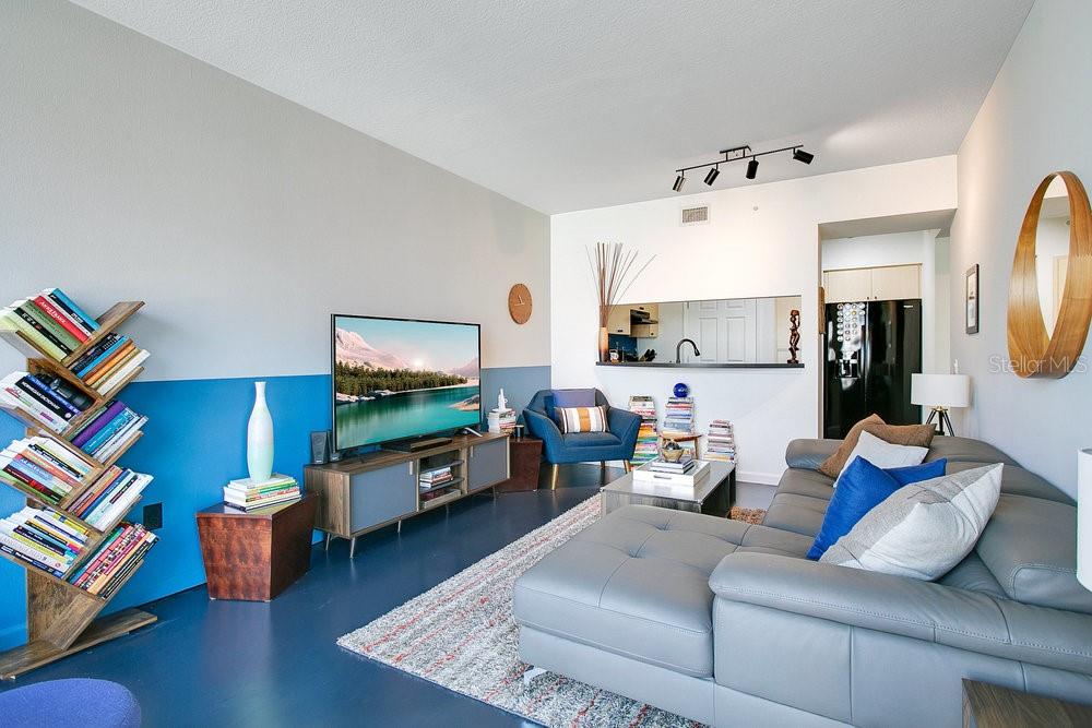 A living room features a grey sectional sofa, a television on a console, and blue walls — 322 E CENTRAL BOULEVARD UNIT 1008, ORLANDO, FL
