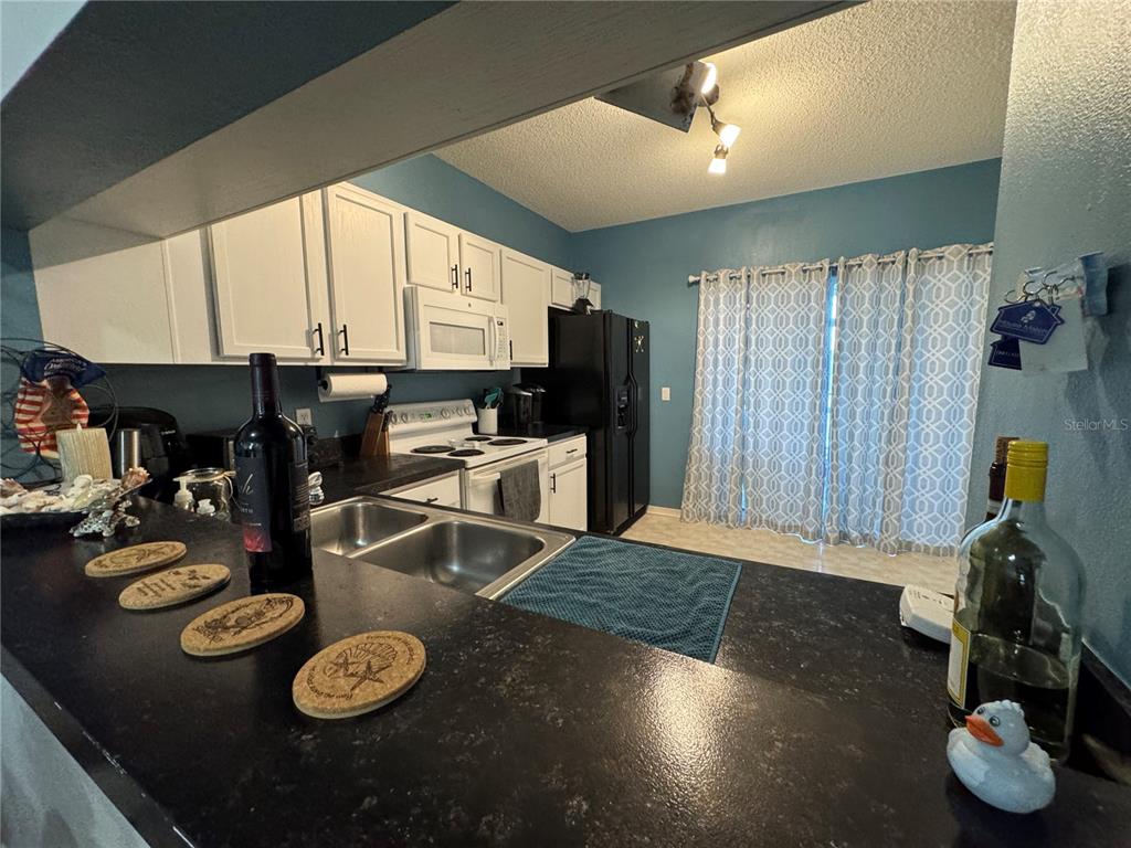 A kitchen features white cabinets, black countertops, a black refrigerator, and a blue accent wall — 4540 RUNABOUT WAY, BRADENTON, FL