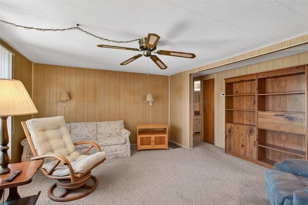 A bedroom features light blue walls, a white bed, a dresser with a mirror, and a ceiling fan — 2000 E BAY DRIVE UNIT 85, LARGO, FL