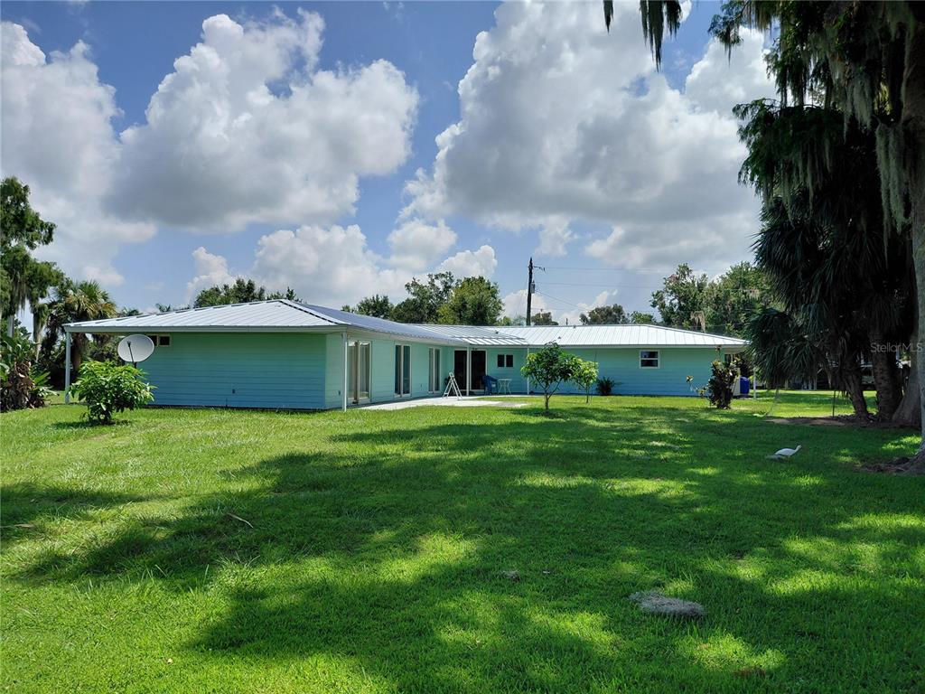 A light blue, single-story house with a metal roof sits on a grassy lawn — 1303 CLUB LANE, LORIDA, FL