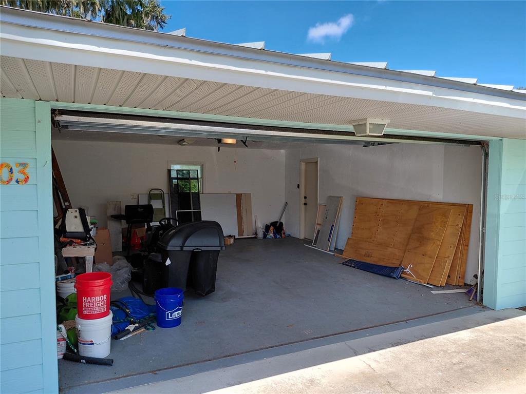 An open garage with a concrete floor, storage items, and a white ceiling — 1303 CLUB LANE, LORIDA, FL