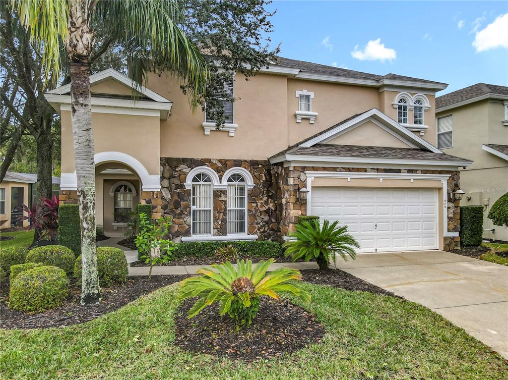 A two-story house with a stone facade, a two-car garage, and a landscaped front yard — 574 TUPELO CIRCLE, DAVENPORT, FL