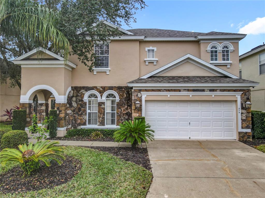 A two-story house with a tan stucco exterior, stone accents, and a two-car garage — 574 TUPELO CIRCLE, DAVENPORT, FL