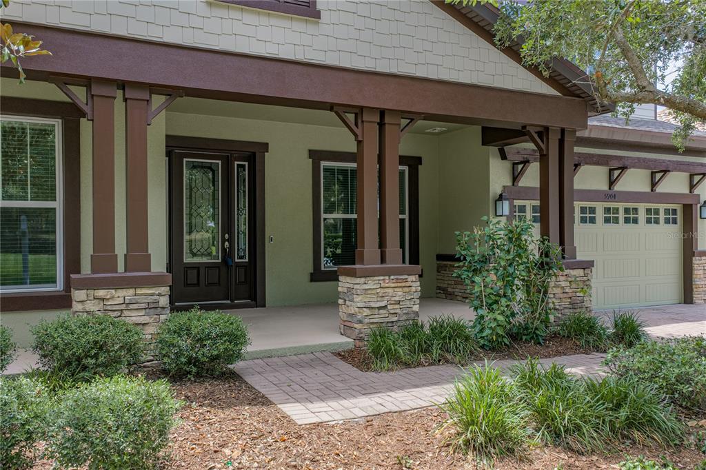 A front porch with stone-based columns leads to a dark wood front door — 5904 SHELL RIDGE DRIVE, LITHIA, FL