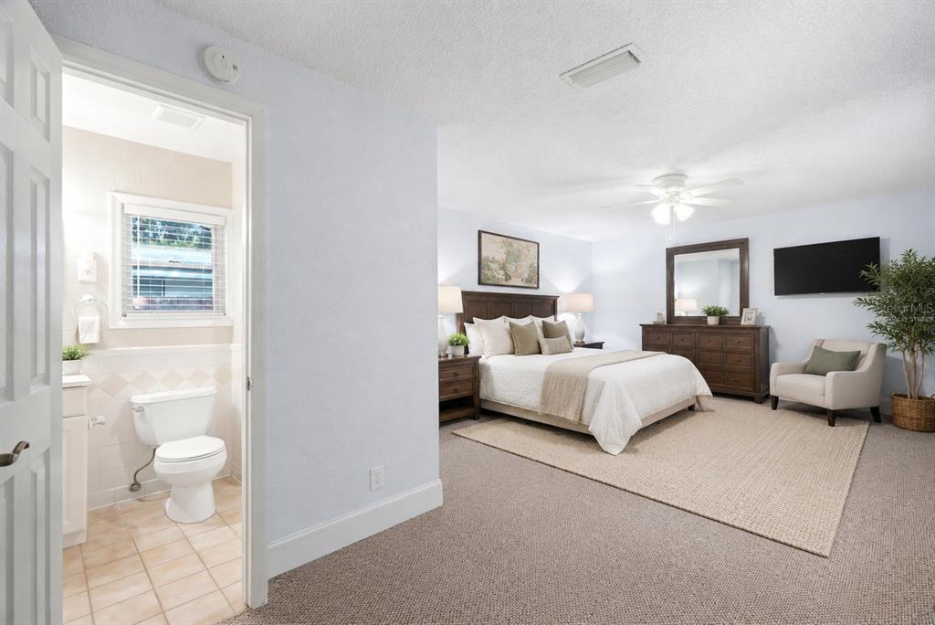 A bedroom with a king bed, carpeted floors, and an attached bathroom with a toilet — 3620 BURLINGTON AVENUE N, ST PETERSBURG, FL