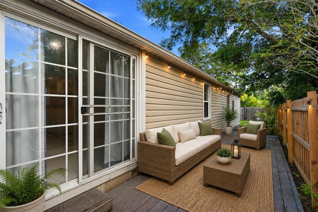 A patio with wicker furniture, a rug, and string lights sits beside a house exterior — 3620 BURLINGTON AVENUE N, ST PETERSBURG, FL
