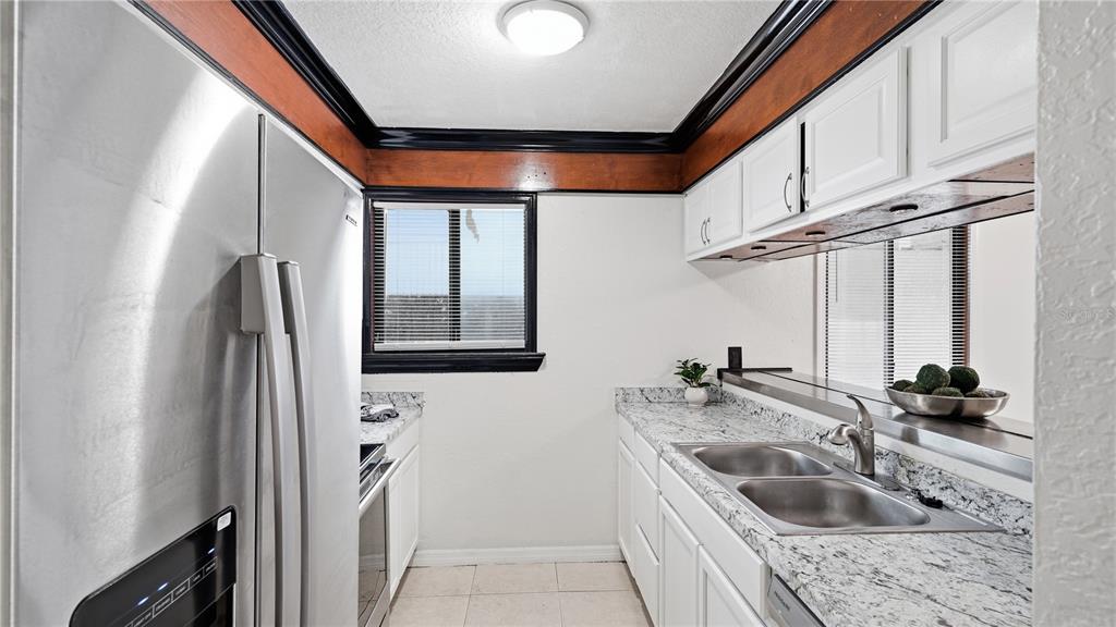 A galley kitchen features white cabinets, granite countertops, stainless steel appliances, and dark wood trim — 1412 OAK PLACE UNIT A, APOPKA, FL