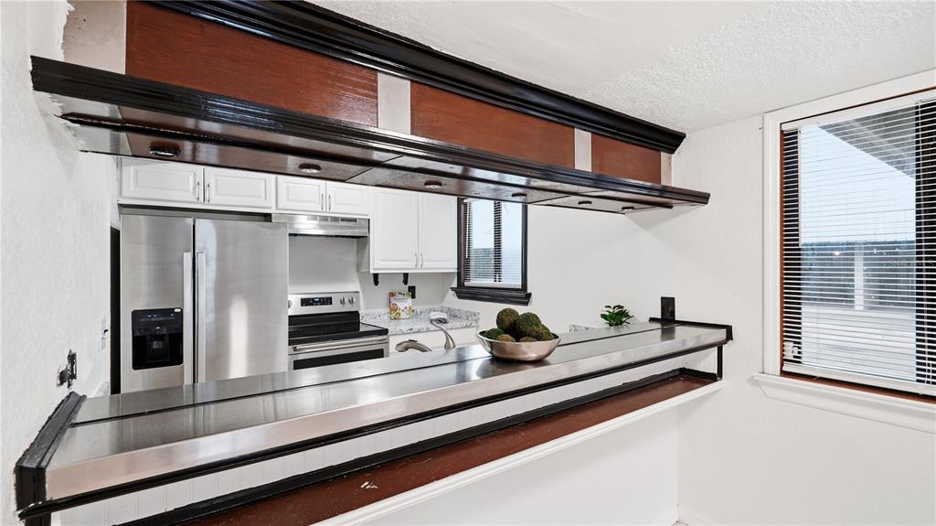 A kitchen features white cabinets, stainless steel appliances, and a long metal breakfast bar — 1412 OAK PLACE UNIT A, APOPKA, FL