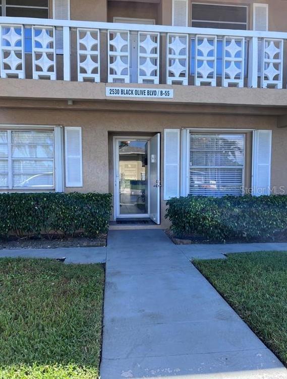 A two-story apartment building exterior features a ground-level entrance, white shutters, and a balcony railing — 2530 BLACK OLIVE BOULEVARD, DELRAY BEACH, FL
