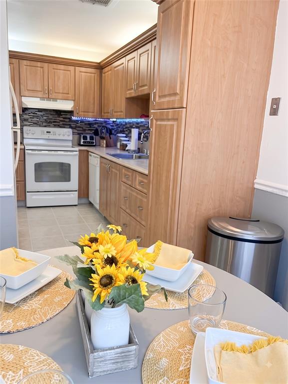 A kitchen with light wood cabinets, a white stove, and a dining table with sunflowers — 2530 BLACK OLIVE BOULEVARD, DELRAY BEACH, FL
