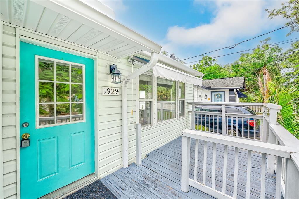 A teal front door opens onto a wooden deck with white railings and siding — 1929 SPRINGTIME AVENUE, CLEARWATER, FL