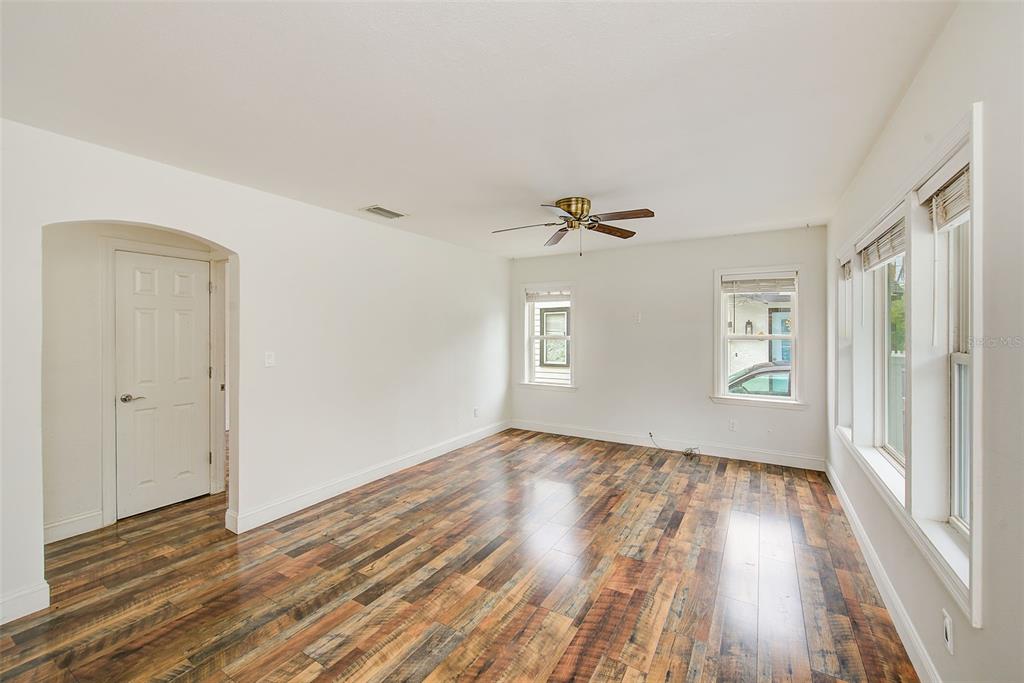 An empty room with white walls, wood-look flooring, a ceiling fan, and multiple windows — 1929 SPRINGTIME AVENUE, CLEARWATER, FL