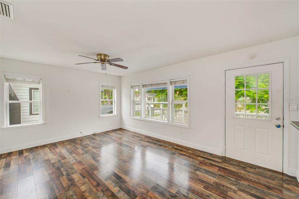An empty room with white walls, wood-look flooring, a ceiling fan, and a white door — 1929 SPRINGTIME AVENUE, CLEARWATER, FL