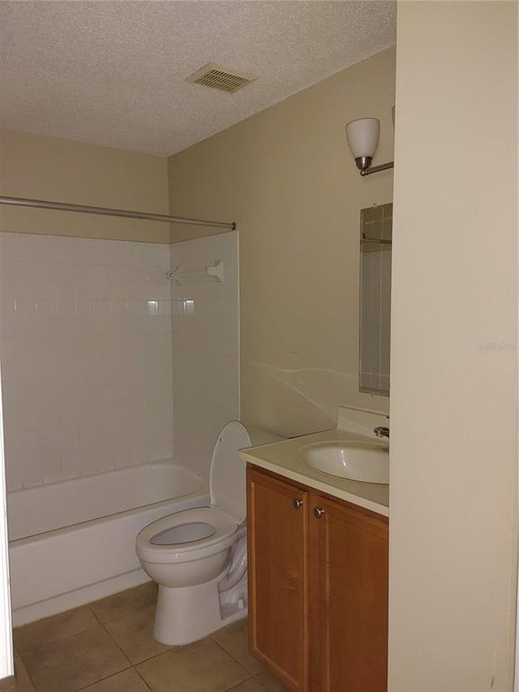 A bathroom features a white bathtub, a toilet, and a vanity with a wood cabinet — 215 LAKE BROOK CIRCLE UNIT 201, BRANDON, FL