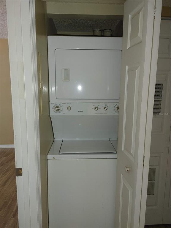 A white stacked washer and dryer unit sits inside a small closet — 215 LAKE BROOK CIRCLE UNIT 201, BRANDON, FL