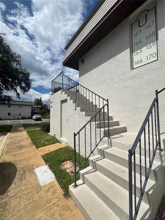 A two-story apartment building exterior with a brown tiled roof and a concrete staircase — 170 WINDTREE LANE, WINTER GARDEN, FL