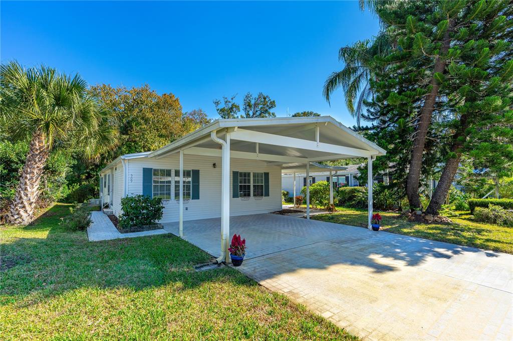 A single-story house with white siding, a paved carport, and surrounding trees and lawn — 509 STARBOARD AVENUE, EDGEWATER, FL