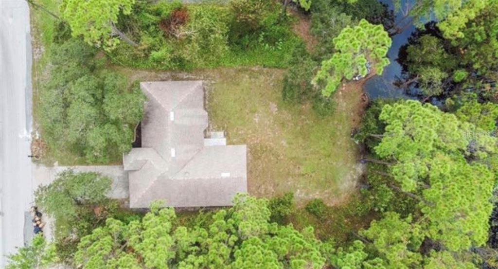 An aerial view shows a house with a shingled roof situated on a wooded lot — 548 GLEN HAVEN DRIVE, DELTONA, FL