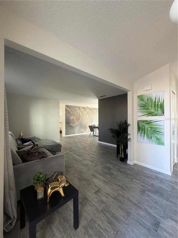 A living room with gray tile flooring, a gray sofa, and a dark accent wall — 548 GLEN HAVEN DRIVE, DELTONA, FL