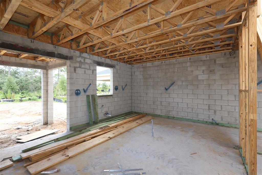 An unfinished room under construction with concrete block walls, exposed wood trusses, and dirt flooring — 5409 PARK GUELL STREET, ST CLOUD, FL