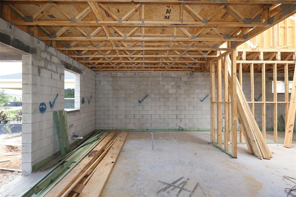 An unfinished room with concrete block walls, exposed wooden roof trusses, and a concrete floor — 5409 PARK GUELL STREET, ST CLOUD, FL