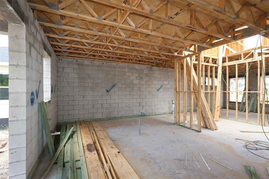 An unfinished room under construction with concrete block walls and exposed wooden roof trusses — 5409 PARK GUELL STREET, ST CLOUD, FL