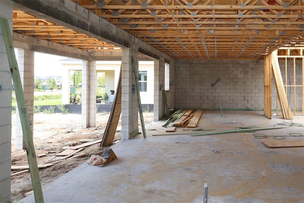 An unfinished room under construction features concrete block walls, exposed wooden roof trusses, and flooring — 5409 PARK GUELL STREET, ST CLOUD, FL