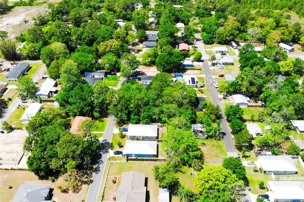 An aerial view shows a residential neighborhood with multiple houses, dense trees, and paved streets — 1028 COLLIER BOULEVARD, ST AUGUSTINE, FL