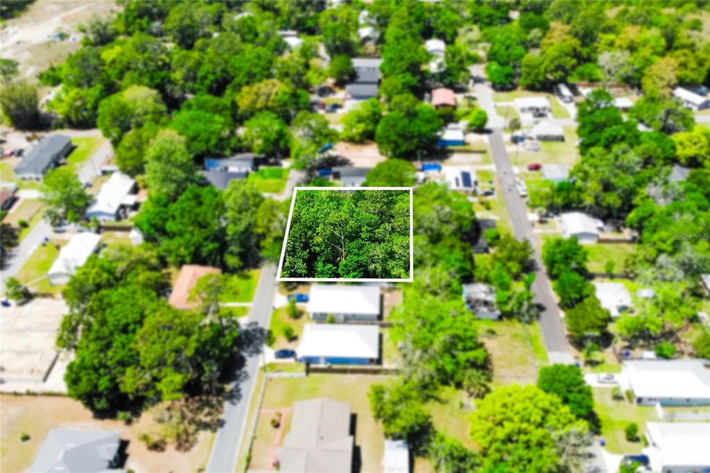 An aerial view shows a rectangular, tree-covered vacant lot highlighted in a residential neighborhood — 1028 COLLIER BOULEVARD, ST AUGUSTINE, FL