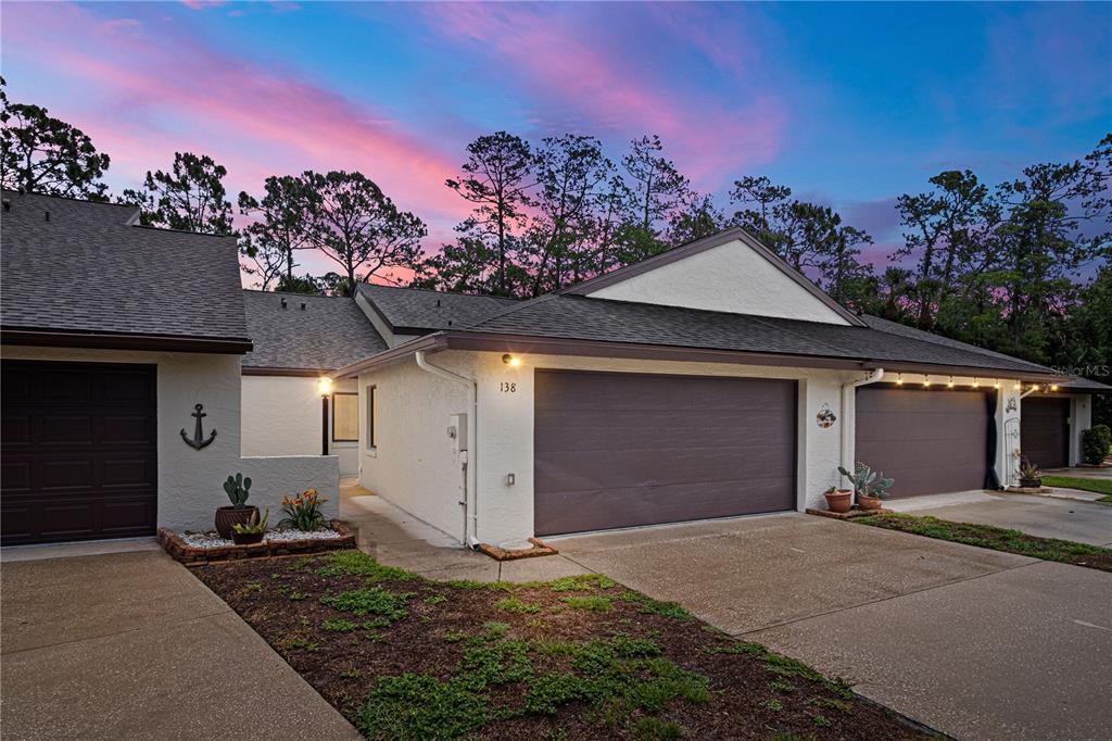 A residential exterior view of a house with a multi-car garage at sunset — 138 FOX FIRE CIRCLE, DAYTONA BEACH, FL