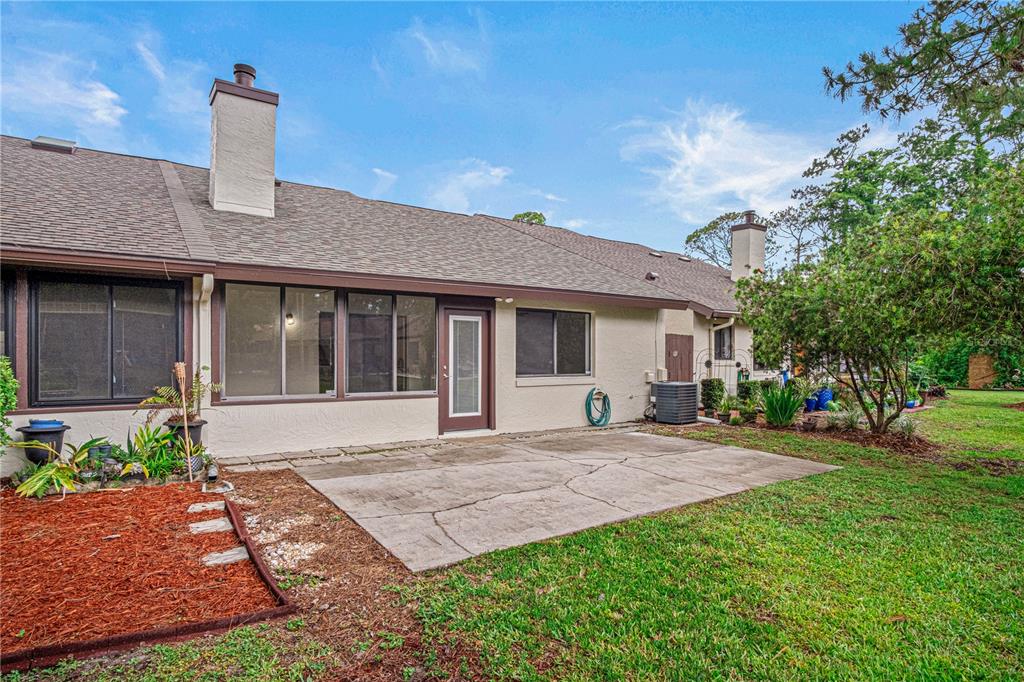 The exterior of a house features a concrete patio, a screened-in porch, and two chimneys — 138 FOX FIRE CIRCLE, DAYTONA BEACH, FL