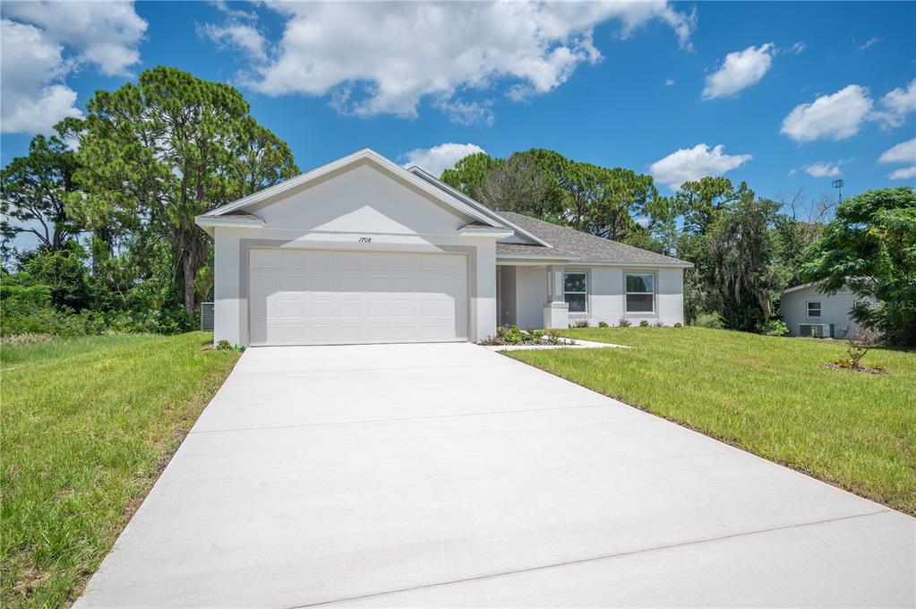A single-story house with a white exterior, a two-car garage, and a concrete driveway — 1708 MANATEE DRIVE, SEBRING, FL