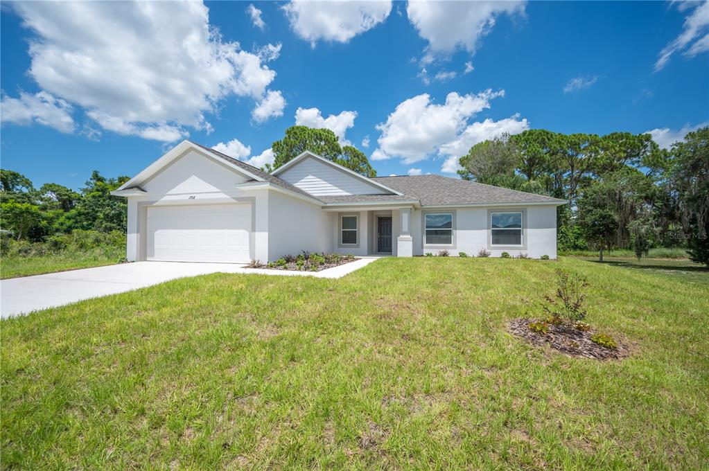 A single-story house with a white exterior, a two-car garage, and a grassy front yard — 1708 MANATEE DRIVE, SEBRING, FL
