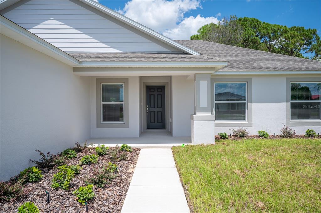 The exterior of a house features a white facade, a dark front door, and a walkway — 1708 MANATEE DRIVE, SEBRING, FL