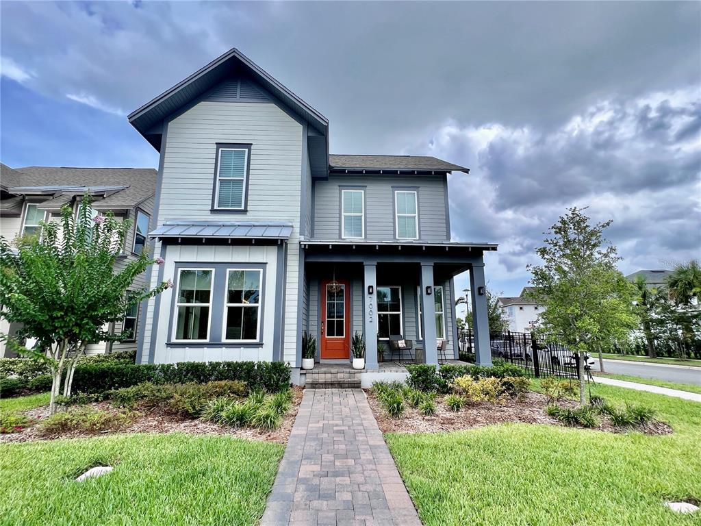 A two-story house with gray siding, a red front door, and a paved walkway — 7002 ARNOLDSON STREET, ORLANDO, FL