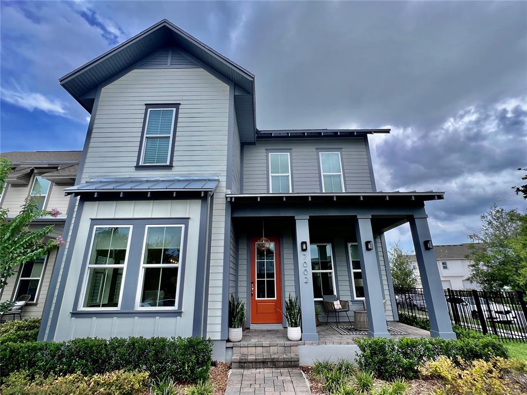 A two-story house with gray siding, a bright orange front door, and a covered porch — 7002 ARNOLDSON STREET, ORLANDO, FL