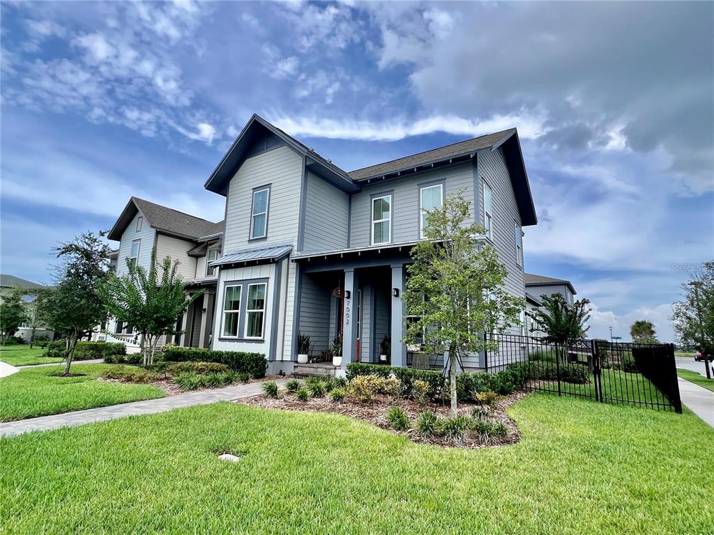 A two-story house with gray siding, a covered front porch, and a fenced side yard — 7002 ARNOLDSON STREET, ORLANDO, FL