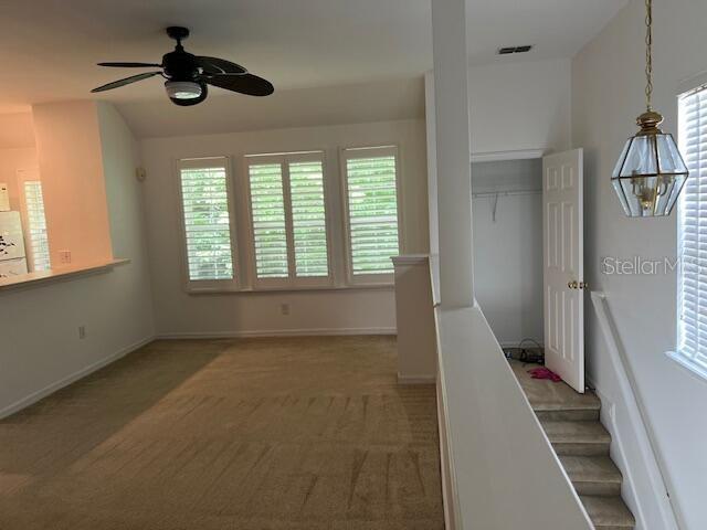 A carpeted room features a ceiling fan, plantation shutters, and a doorway leading to stairs — 947 SPRING PARK LOOP APT B, KISSIMMEE, FL