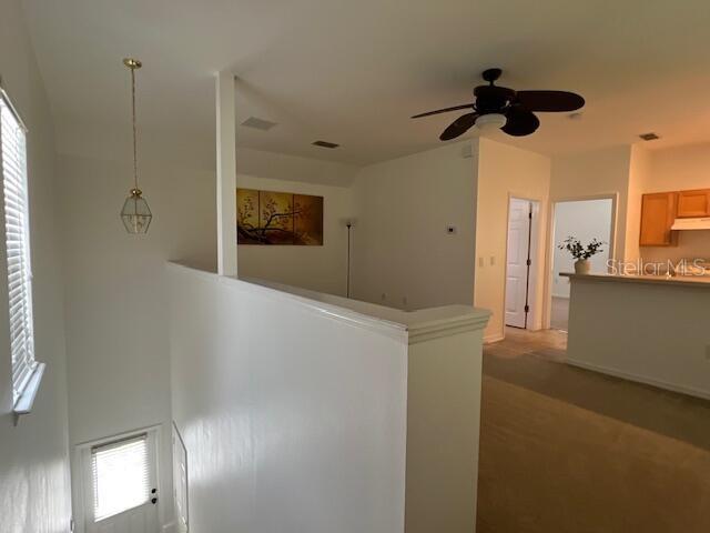 An interior view shows a staircase landing with a ceiling fan and a kitchen beyond — 947 SPRING PARK LOOP APT B, KISSIMMEE, FL