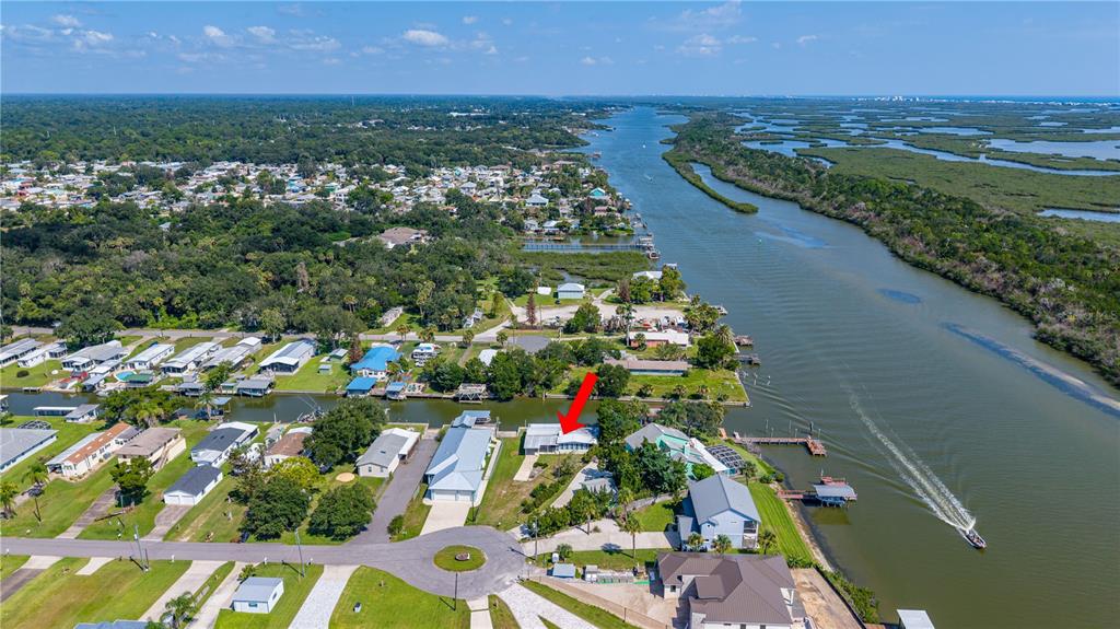 An aerial view shows a waterfront house with a red arrow pointing to its roof — 286 RANDLE AVENUE, OAK HILL, FL