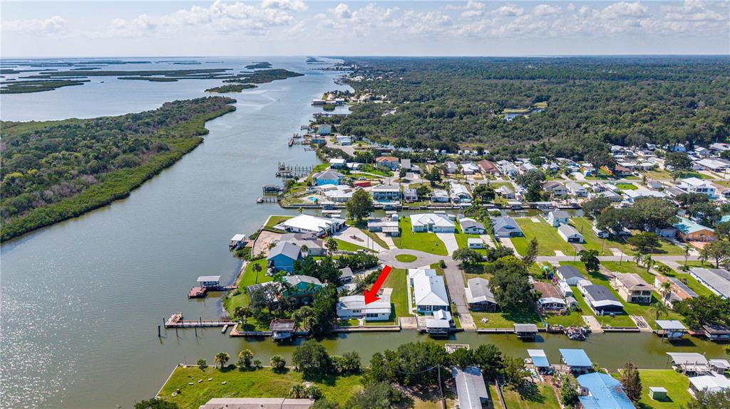 An aerial view of a waterfront house with a red arrow pointing to the roof — 286 RANDLE AVENUE, OAK HILL, FL