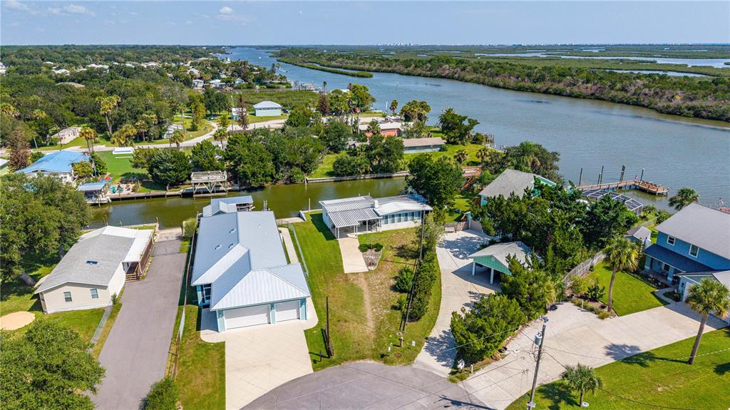 An aerial view shows several waterfront houses with metal roofs and driveways near a canal — 286 RANDLE AVENUE, OAK HILL, FL