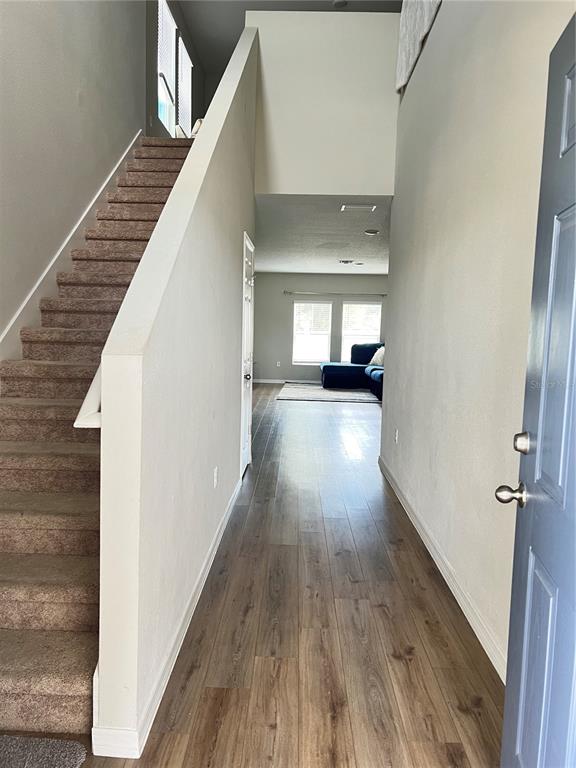 An entryway features wood-look flooring, a carpeted staircase with a white railing, and a high ceiling — 5377 MADDIE DRIVE, HAINES CITY, FL