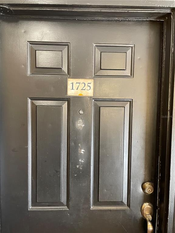 A black front door with a silver peephole and the number 1725 mounted above — 4512 COMMANDER DRIVE UNIT 1725, ORLANDO, FL