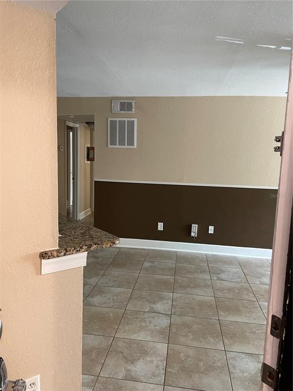 An interior view shows a room with tiled floors, two-tone walls, and a granite countertop — 4512 COMMANDER DRIVE UNIT 1725, ORLANDO, FL