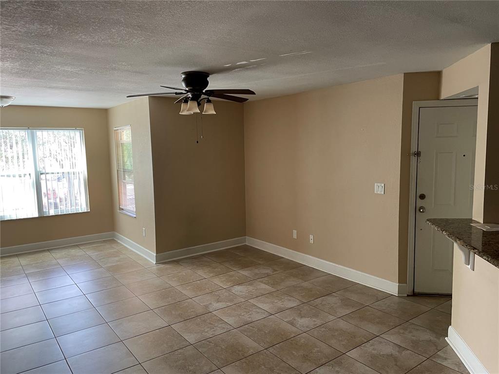 An empty room with tan walls, tile flooring, a ceiling fan, and a white door — 4512 COMMANDER DRIVE UNIT 1725, ORLANDO, FL