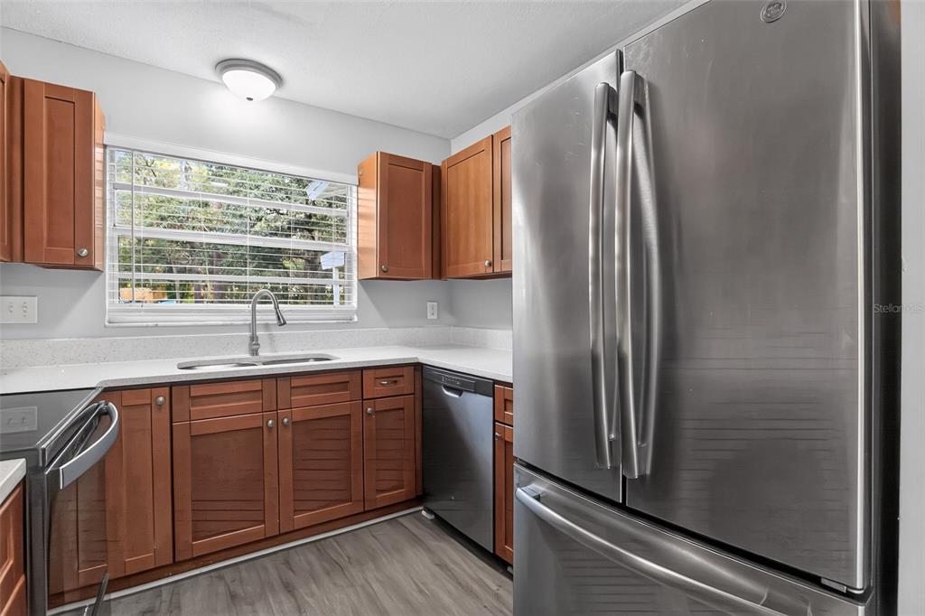 A kitchen features wood cabinets, stainless steel appliances, a window above the sink, and light flooring — 26430 SLEEPY HOLLOW STREET, MOUNT PLYMOUTH, FL